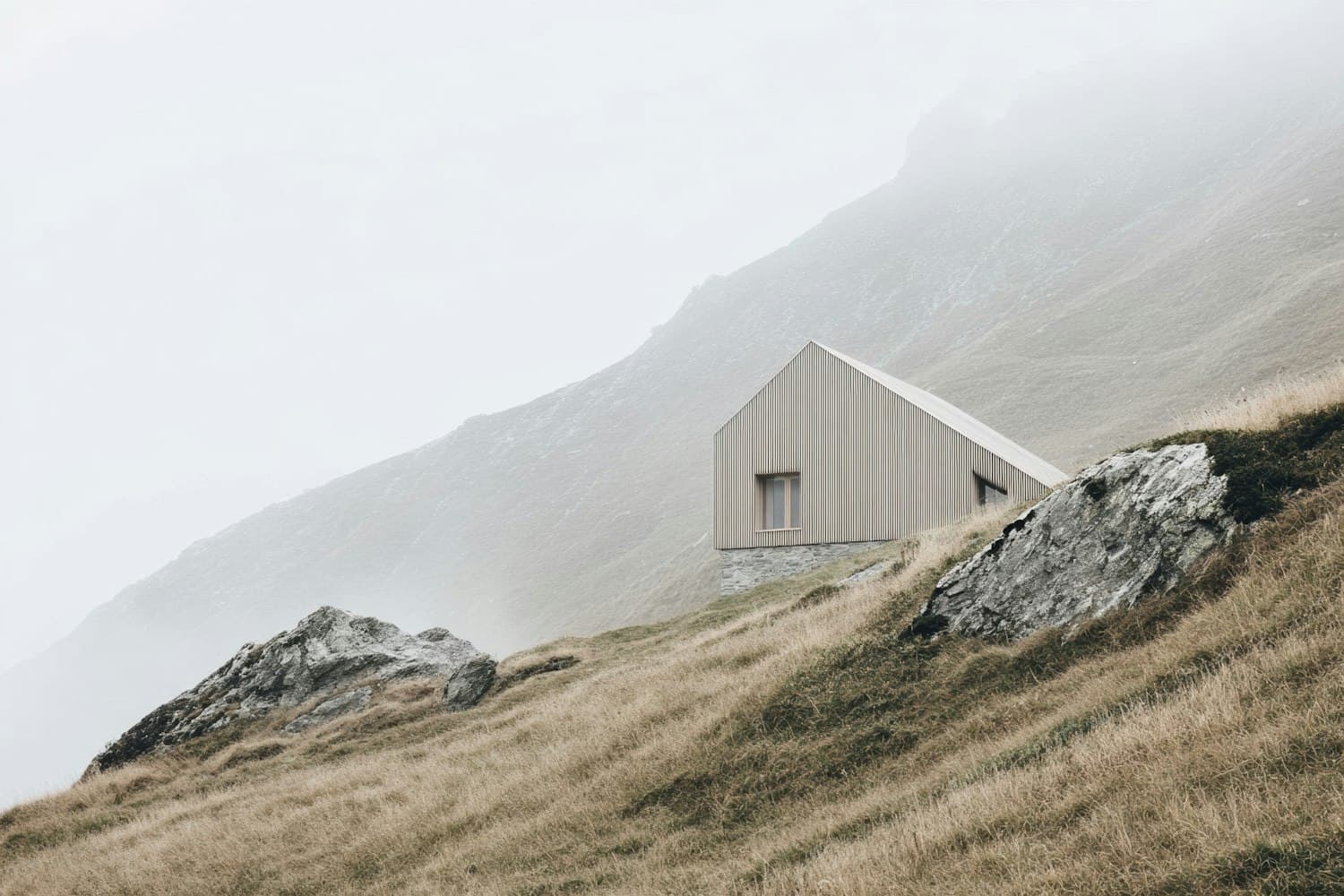 A timber lodge on a stone base, set into a grassy hillside